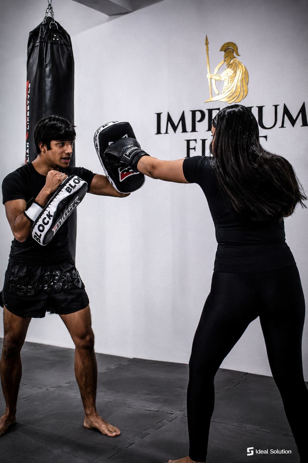 Aluno treinando socos no aparador dentro do tatame da Imperium Fight